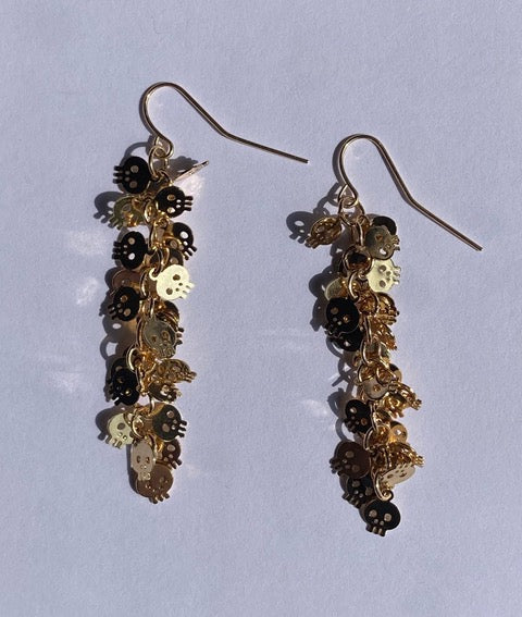 A pair of earrings featuring metallic gold and gunmetal colored dangles with tiny skull designs and black accents.